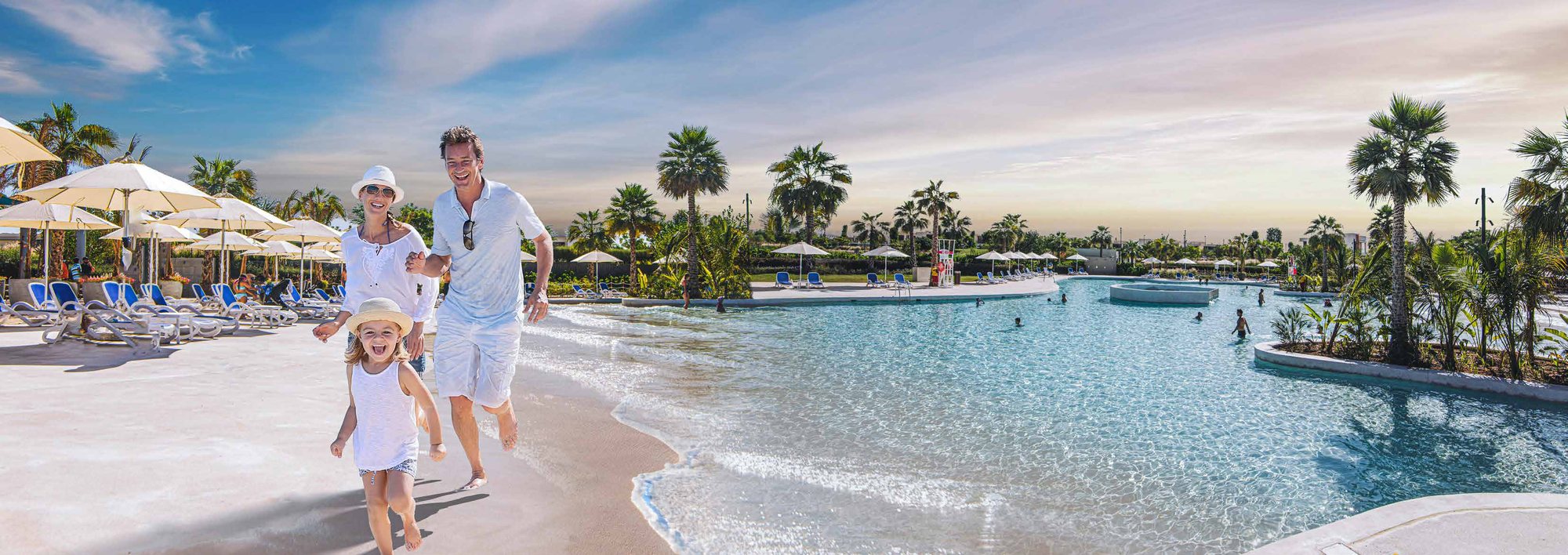 Family on the sandy beach edge of a DAMAC crystal lagoon pool